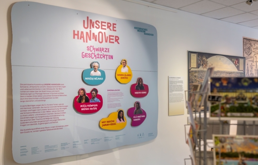 Tafel mit den Porträts der Ausstellungskurator*innen