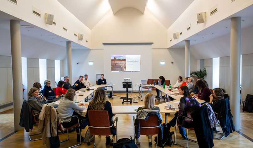 Workshop im Black History Month, 19 Frauen und Männer sitzen an U-förmig aufgestellten Tischen, im Hintergrund eine Präsentation auf einer Leinwand