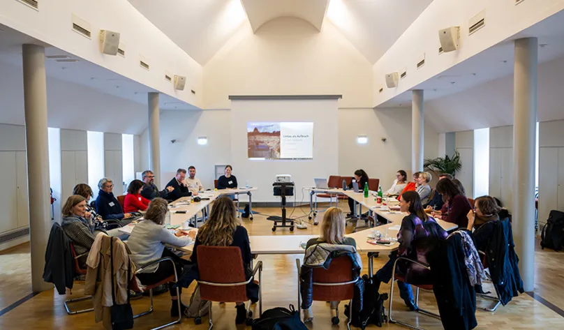 Workshop im Black History Month, 19 Frauen und Männer sitzen an U-förmig aufgestellten Tischen, im Hintergrund eine Präsentation auf einer Leinwand