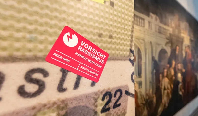 Blick in die Sonderausstellung "Von goldenen Kutschen und kolonialer Vergangenheit: Hannover, England und die Sklaverei", vom 12. Juli bis 13. November 2022 im HMH, hier der rechteckige rote Sticker "Vorsicht Rassismus"