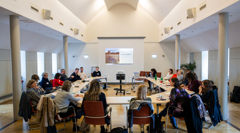 Workshop im Black History Month, 19 Frauen und Männer sitzen an U-förmig aufgestellten Tischen, im Hintergrund eine Präsentation auf einer Leinwand